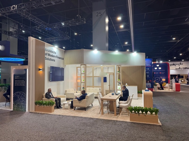 Light wood slat and white exhibition stand with lounge seating and meeting table at SIBOS 2026, Miami